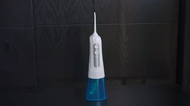 Cordless dental water flosser running on a table without water. Uncompressed 24 bit high quality sound. Oral care technology and dental health concept.
