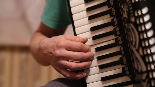 Hands move over accordion keys, creating music in a cozy room filled with friends and laughter late at night.