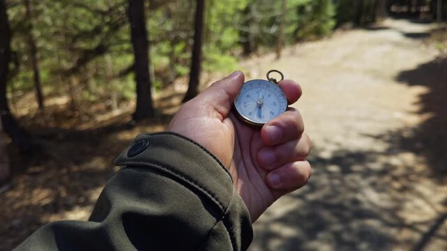 A hand holds a vintage compass, guiding the way through a serene forest trail. Sunlight filters through the trees, illuminating the peaceful surroundings. Nature beckons adventurers