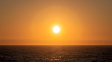 Obraz premium Sunrise over calm open ocean waters with golden sunlight