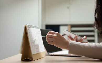 Businesswoman managing schedule and business planning with calendar and smartphone, representing task organization, appointment management, workflow planning, and productivity strategy. © Father_Studio