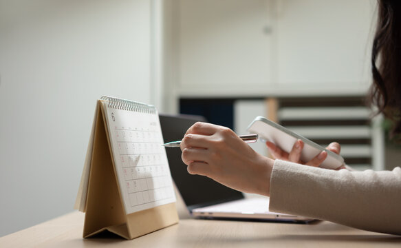 Businesswoman managing schedule and business planning with calendar and smartphone, representing task organization, appointment management, workflow planning, and productivity strategy.