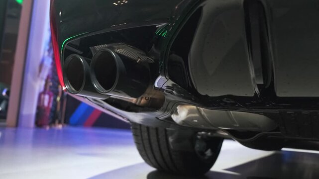 Detailed low-angle shot of dual exhaust pipes and rear diffuser on a modern performance sedan, emphasizing sporty engineering and premium automotive craftsmanship. Cinematic close-up view