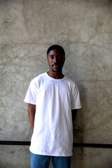 Fototapeta premium Man in white t-shirt and jeans standing against a textured wall.