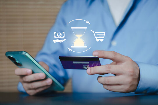 Processing online payment concept with hourglass icon. Businessman using credit card and smartphone for pending transaction, financial waiting time, and digital ecommerce shopping transfer.
