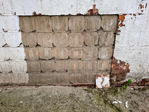 Weathered wall shows missing tiles and concrete blocks during building renovation in urban area