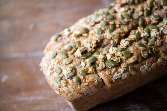 Close-up of a loaf of multigrain bread with seeds on a wooden table.