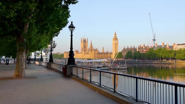 The London riverside of the Thames at Southbank with view to the Big Ben tower and Westminster Palace during a summer sunrise without people, United Kingdom