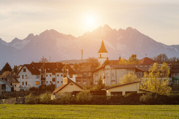 Fototapeta premium Small mountain village at sunset with church tower