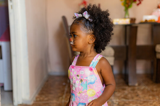 Beautiful 2-year-old black girl celebrating Easter at home receiving gifts.