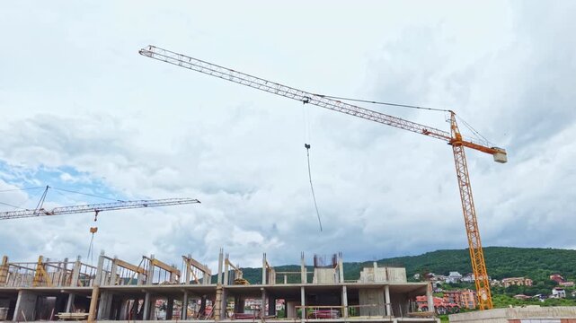 Crane flock over construction site under brooding clouds, concrete frame rising beside distant green hills, birds in migration tracing crane jib, slow cinematic