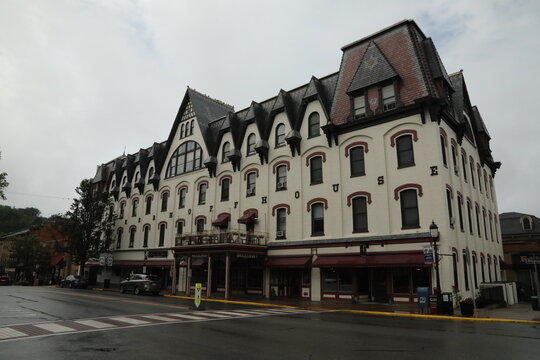 A large historic downtown building with arched windows, mansard roof sections, and storefronts on a wet street in Bellefonte, Pennsylvania. Added to the National Register in 1977