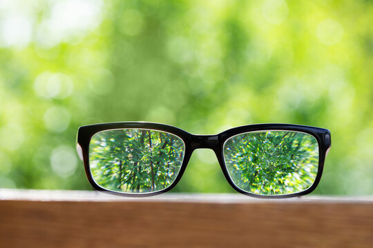 Clear vision through spectacles on blurred nature background, choosing glasses for sharp view and eyesight correction for focused view.