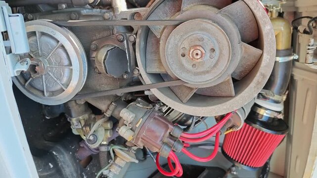 Close-up view of an automotive engine showing detailed components, including belts, pulleys, and hoses, highlighting the mechanical intricacies in a well-lit garage setting