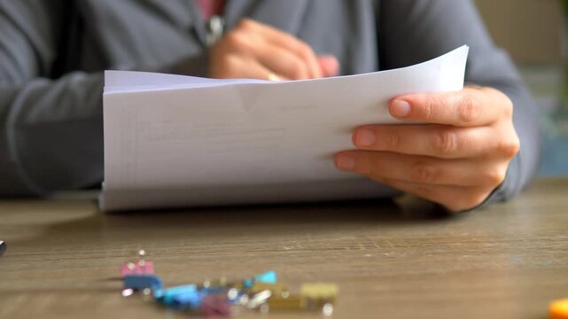 Removing Pink Binder Clip from Invoice Stack Close Up &mdash; Hands Unclipping Financial Documents, Bookkeeping Tax Prep and Business Receipts Audit
