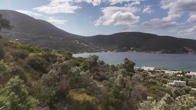 4K aerial view of Vathi bay and fishing village framed by olive groves, Sifnos Island, Greece