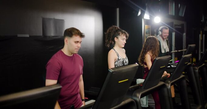 Group of friends exercises together in fitness center using treadmills and enjoys physical activity with support and encouragement