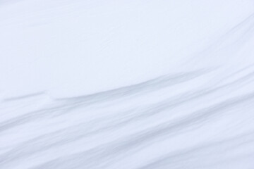 Obraz premium Soft wind-sculpted snow drifts form a minimal, serene white texture with gentle ridges and blue-gray shadows. Clean, cold and abstract winter surface ideal for backgrounds, design and seasonal concept