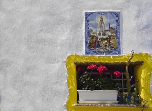 Handmade glazed tile religious icon against a whitewashed wall in Borgo dei Parrini Sicily, Italy.