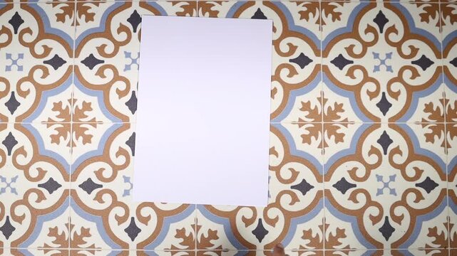 Person holding white empty paper A4 on tiles backdrop
