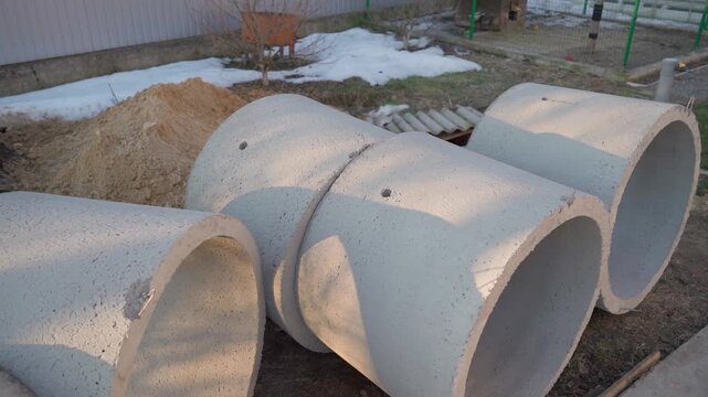 Concrete well rings lying on ground at construction site for septic tank installation