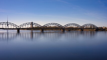 Fototapeta premium Railway Bridge over Daugava River reflecting in calm water in Riga Latvia