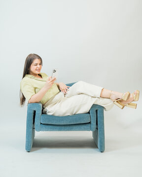 Woman Relaxing on Blue Chair Using Smartphone