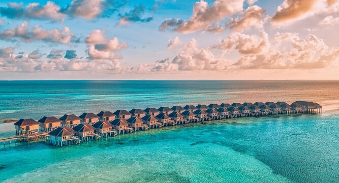 Aerial Maldives overwater villas turquoise lagoon dramatic cloudy sky luxury resort tropical island Indian Ocean stunning drone view exotic paradise getaway honeymoon escape moody atmospheric seascape