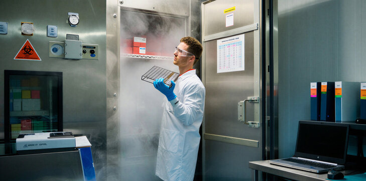 Scientist in lab coat inspecting cryogenic storage freezer in modern research facility with scientist cryogenic laboratory research biotechnology specimen technology pharmaceutical