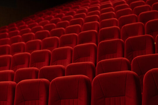 Empty cinema auditorium with rows of red velvet seats and ceiling lights