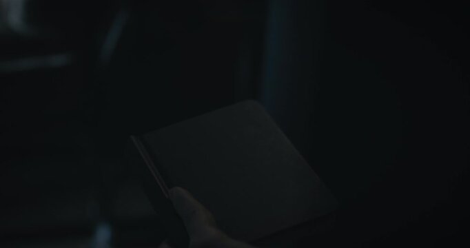 Notebook with objectives written inside being raised up in darkness and dim flashlight coming on - closeup