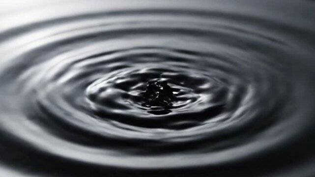 Water Droplet Splash Creating Ripples On Dark Reflective Surface