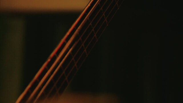 Close up of heavy metal bassist's hand playing riff on fretboard. Dark, moody scene with intense blue stage lighting. Concept for live music, concerts, and rock band performance