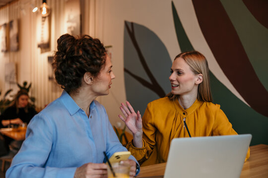 Women coworkers talking during business meeting at cafe