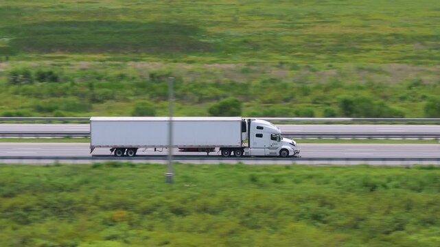 Aerial view of semi-truck driving on busy American interstate freeway. Delivering cargo concept.