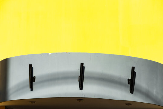 Minimal yellow facade rises above curved blue architectural canopy