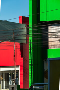 Vibrant red and green urban facade intersects overhead wire and sharp shadow