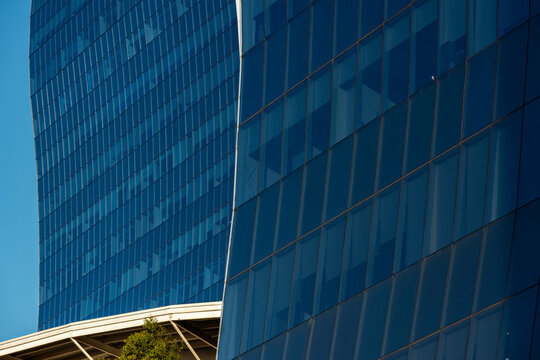 Curved blue glass facade bends through vertical rhythm above angular canopy