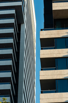 Facing towers frame a narrow vertical gap of blue sky