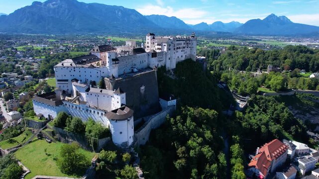Salzburg Austria 4k drone footage of Hohensalzburg fortress. Cinematic aerial side fly from white medieval castle to old town cityscape and Alpine mountains