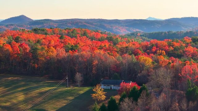 Appalachian mountain rural landscape with orange and yellow forest trees. Tennessee houses appear between rolling hills and colorful foliage
