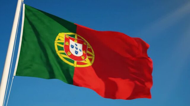 Flag of portugal waving on flagpole against clear blue sky
