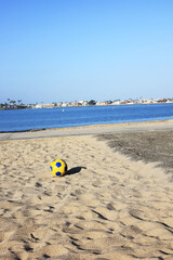 Obraz premium Bright beach soccer ball resting on warm Sail Bay sand under clear San Diego sky, California