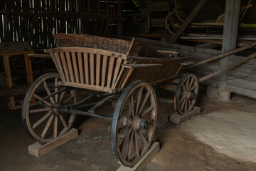 Obraz premium Vintage wooden cart stands inside an old rustic barn. Traditional agricultural vehicle from past centuries for historical museum exhibition and eco tourism concepts