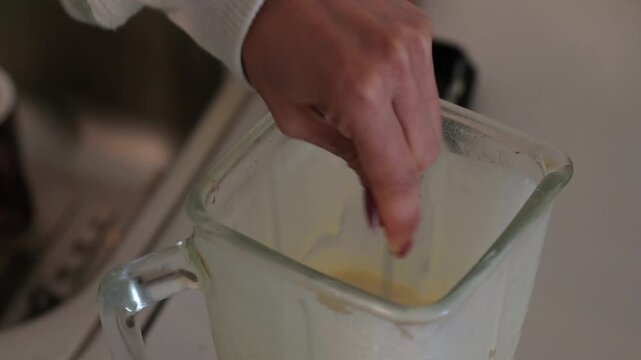 4k video of a woman preparing pancakes, stirring the batter in the blender with a spoon to make them
