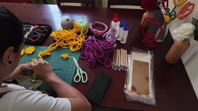 Artisan woman crafting yellow yarn flowers at home