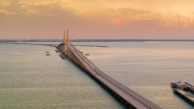Transportation infrastructure of Florida, USA. Sunshine Skyway Bridge over Tampa Bay with driving traffic cars at sunset