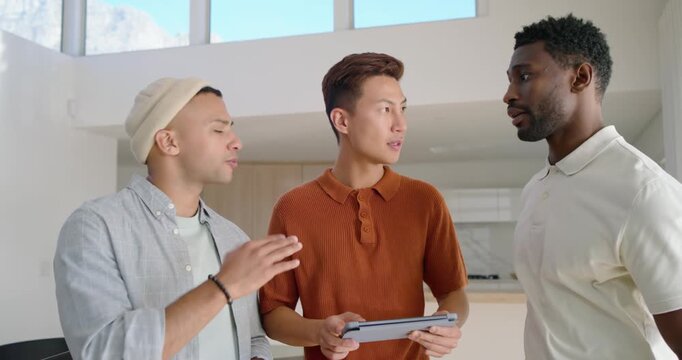 Diverse male friends responding to tablet content, tapping and pointing in kitchen, posing smiling