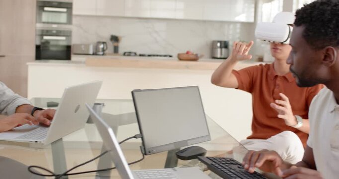 Diverse male team, arrival, laptop typing at glass table, VR user white headset testing, copy space