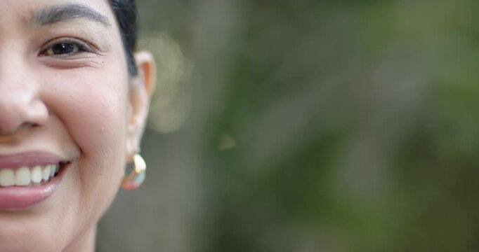 Adult female reacting to offscreen prompt, smiling and laughing outdoors, gold hoops, copy space